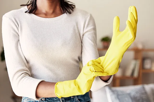 recorte mujer colcandose guantes amarillos de limpieza